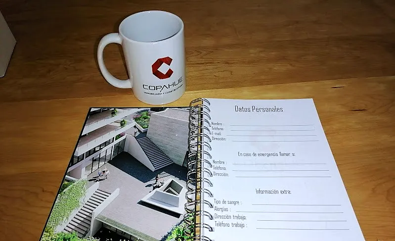 Tazón blanco con el logo de Copahue junto a una agenda anillada abierta