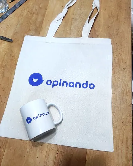 Bolsa de tela cruda y tazón blanco con el logo azul de Opinando
